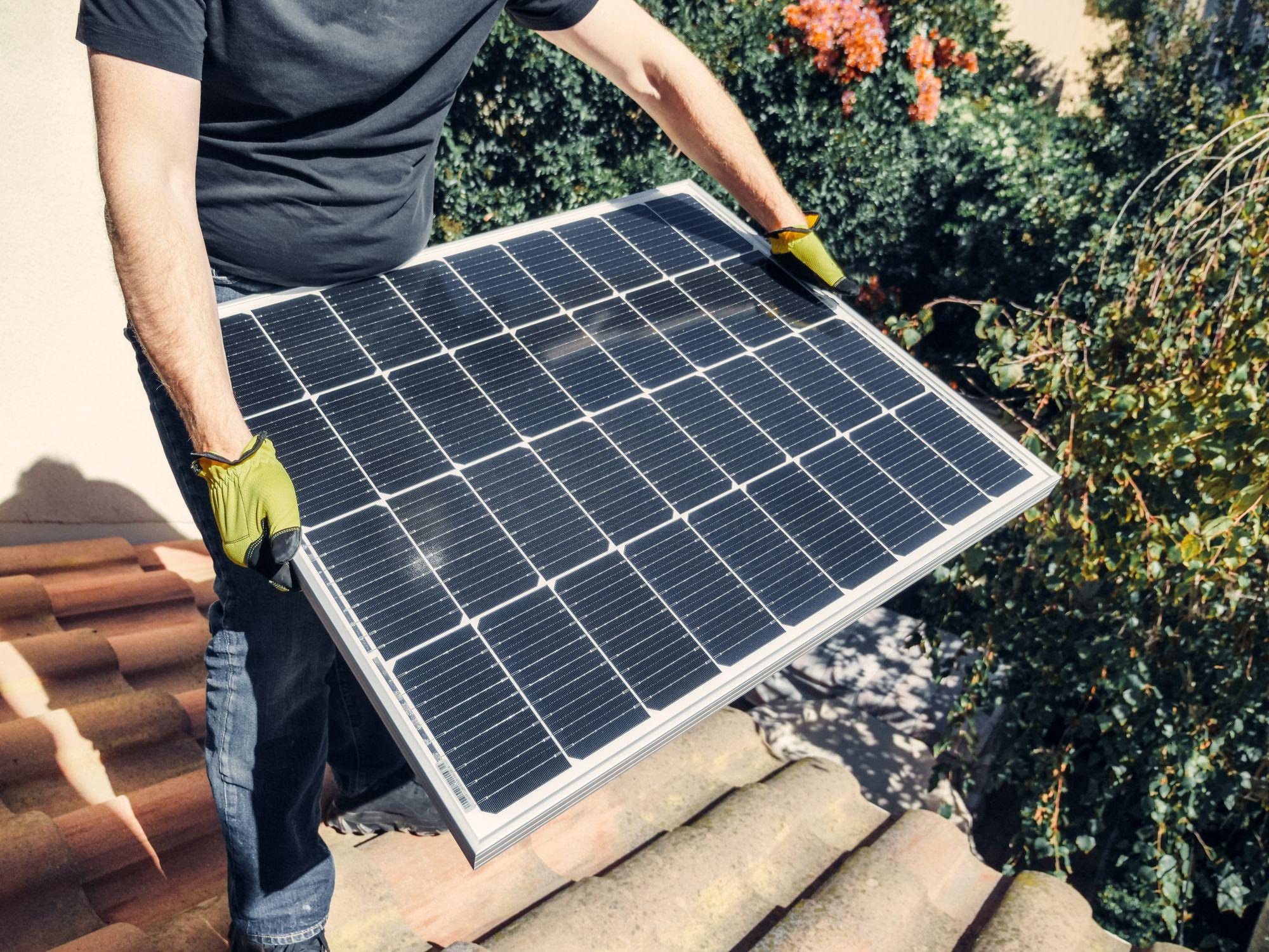 Installer placing a solar panel on a rooftop